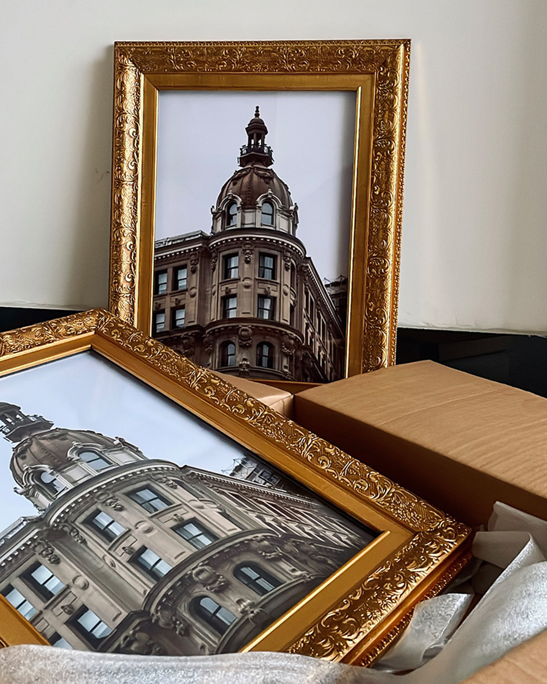Elegant wall art in gold frame leaning against a white wall