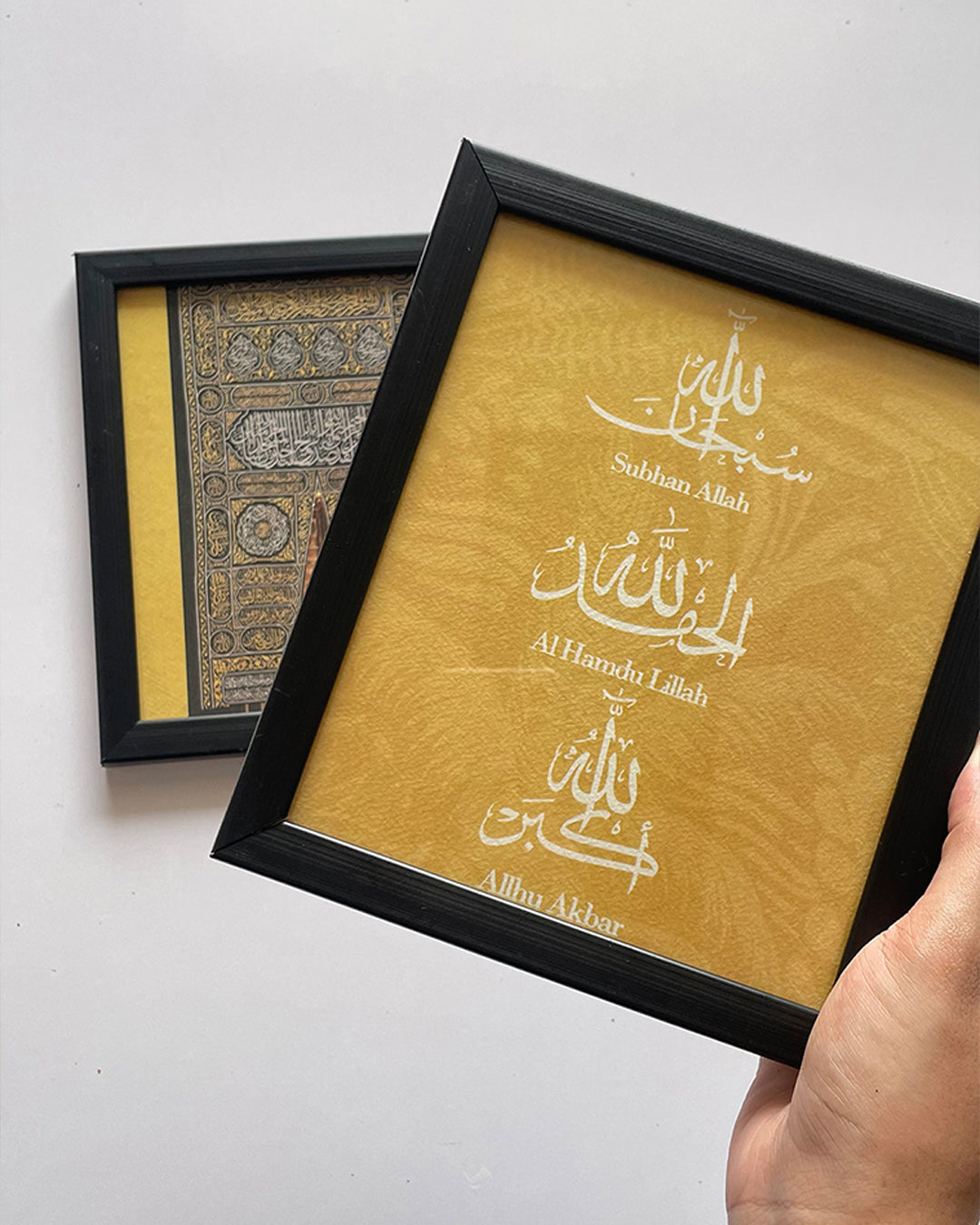 Person holding two mini frame artworks for size comparison