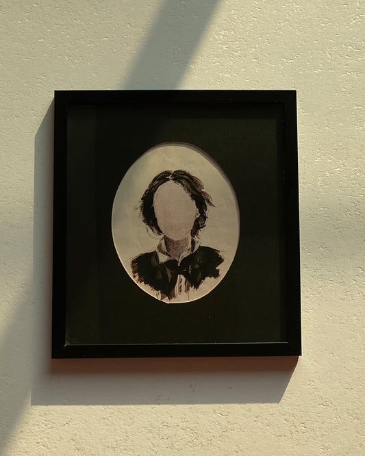 Framed portrait painting in a black frame displayed on a beige wall